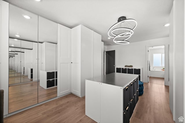 1067 W Ludington Ct, Bluffdale, UT 84065 - kitchen featuring light wood-style flooring, dark cabinetry, a kitchen island, recessed lighting, and light countertops