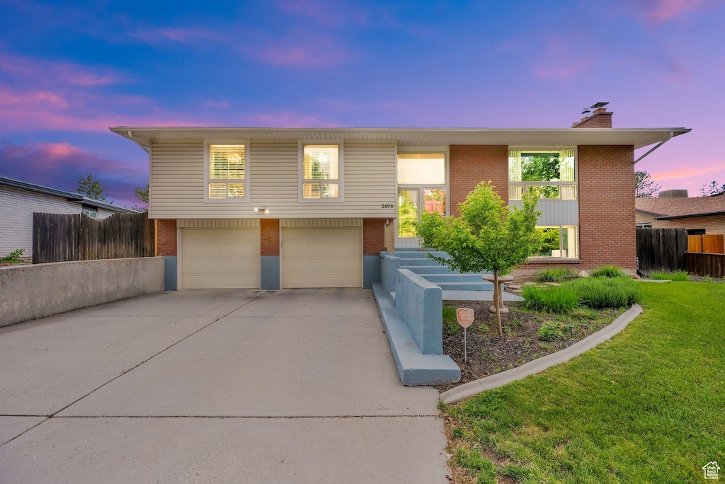 2406 E Nantucket Dr, Cottonwood Heights, UT 84121 - split foyer home with brick siding, an attached garage, concrete driveway, and a chimney