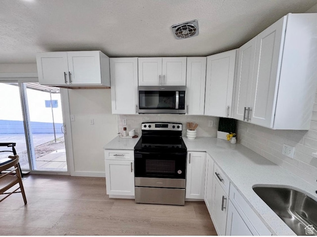 5011 S Leisure Ln W, Taylorsville, UT 84129 - kitchen featuring appliances with stainless steel finishes, light countertops, a textured ceiling, white cabinetry, and decorative backsplash