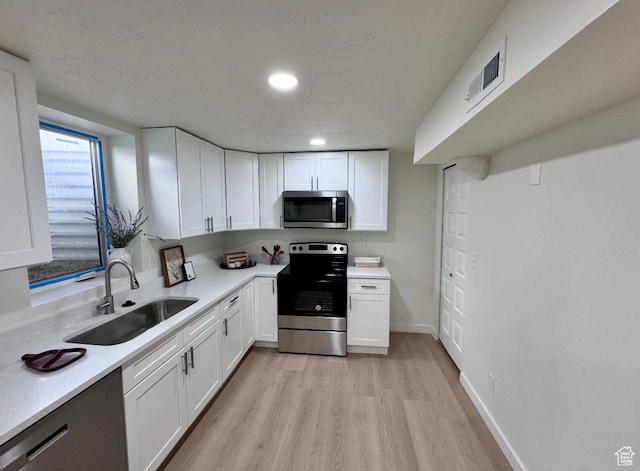 5011 S Leisure Ln W, Taylorsville, UT 84129 - kitchen featuring stainless steel appliances, a sink, light wood finished floors, white cabinetry, and light countertops