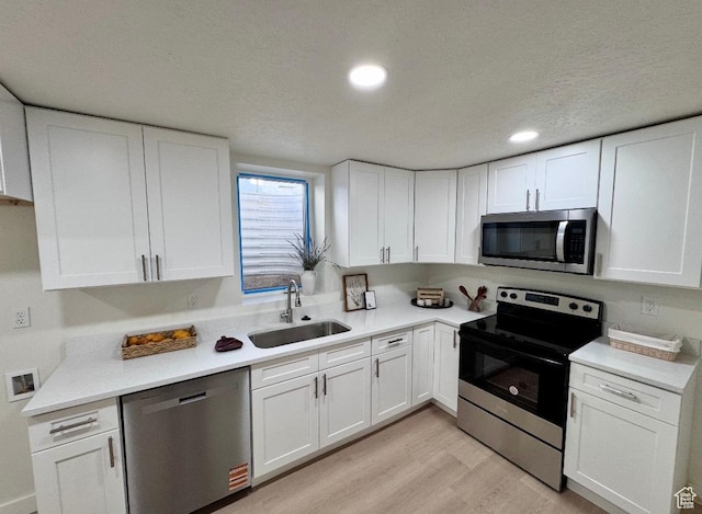5011 S Leisure Ln W, Taylorsville, UT 84129 - kitchen with stainless steel appliances, a sink, light wood-style floors, white cabinets, and recessed lighting