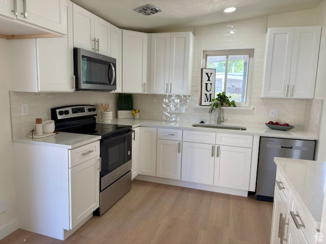 5011 S Leisure Ln W, Taylorsville, UT 84129 - kitchen with stainless steel appliances, a sink, white cabinets, and tasteful backsplash