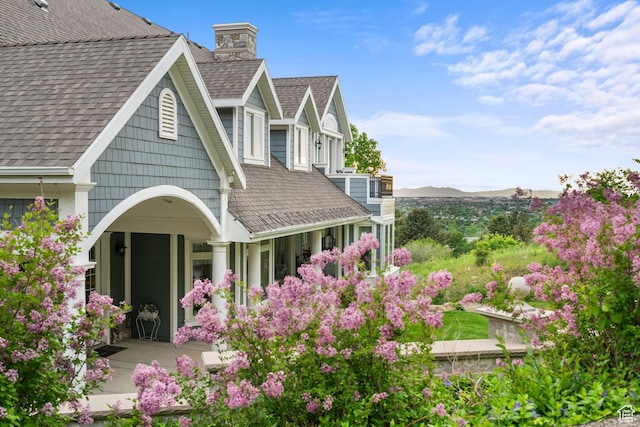 3291 E 1300 N, Layton, UT 84040 - back of house with a shingled roof, a chimney, a mountain view, and a porch