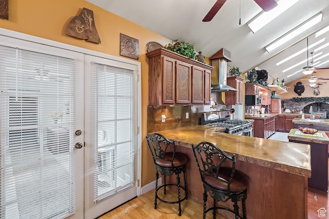 154 E 950 N, Glenwood, UT 84730 - kitchen featuring appliances with stainless steel finishes, ceiling fan, wall chimney exhaust hood, vaulted ceiling, and a peninsula