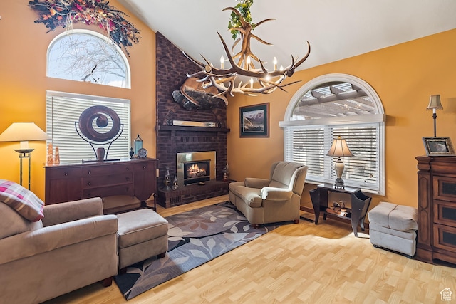 154 E 950 N, Glenwood, UT 84730 - living room featuring wood finished floors, a chandelier, high vaulted ceiling, and a brick fireplace