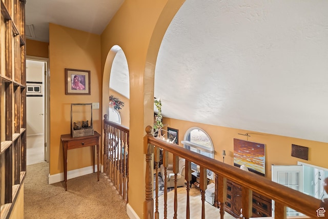 154 E 950 N, Glenwood, UT 84730 - hallway featuring arched walkways, light colored carpet, baseboards, an upstairs landing, and a textured ceiling