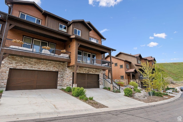 1757 E Longview Dr Unit 87, Hideout, UT 84036 - view of front facade featuring stone siding, a balcony, a garage, and concrete driveway