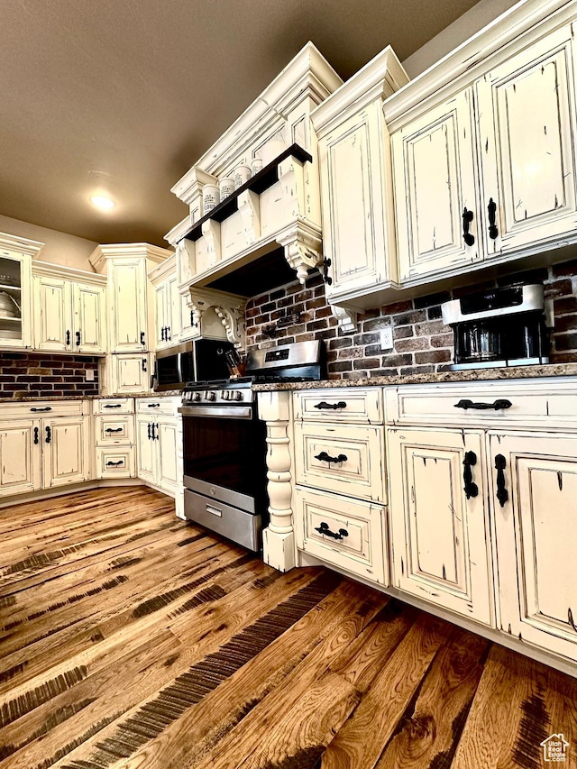 1471 N 3500 E, Ballard, UT 84066 - kitchen with stainless steel appliances, cream cabinets, dark countertops, backsplash, and dark wood finished floors