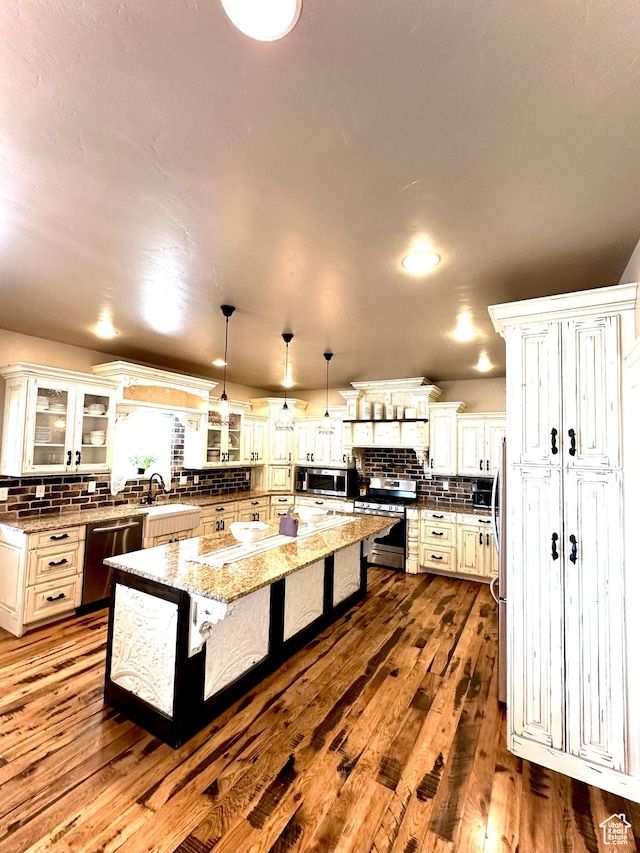 1471 N 3500 E, Ballard, UT 84066 - kitchen featuring appliances with stainless steel finishes, decorative backsplash, a center island, a kitchen bar, and dark wood finished floors
