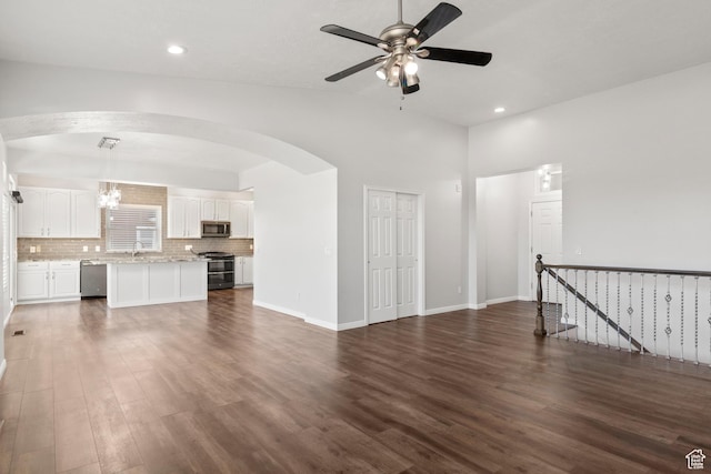 8793 S Mountain Vista Dr, West Jordan, UT 84081 - unfurnished living room featuring dark wood-style floors, arched walkways, ceiling fan, recessed lighting, and a sink