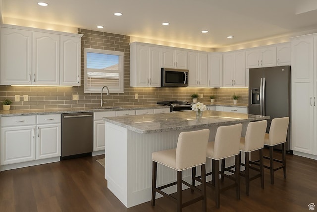 8793 S Mountain Vista Dr, West Jordan, UT 84081 - kitchen with stainless steel appliances, a sink, dark wood-style flooring, a kitchen bar, and white cabinets