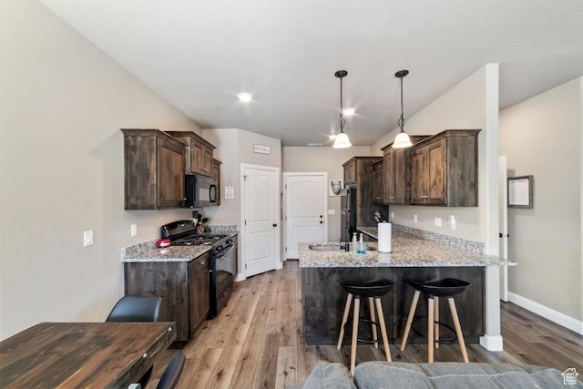 404 W 1325 N Unit L5, Cedar City, UT 84721 - kitchen with black appliances, dark brown cabinets, light wood-style floors, a peninsula, and a breakfast bar