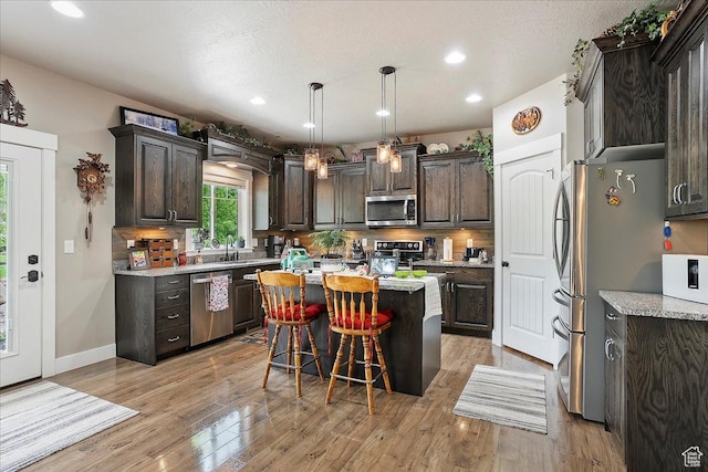 4548 N Sheep Creek Dr, Eden, UT 84310 - kitchen featuring stainless steel appliances, dark brown cabinetry, a center island, a breakfast bar, and backsplash