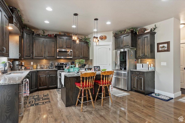 4548 N Sheep Creek Dr, Eden, UT 84310 - kitchen with appliances with stainless steel finishes, a sink, dark brown cabinetry, a center island, and tasteful backsplash