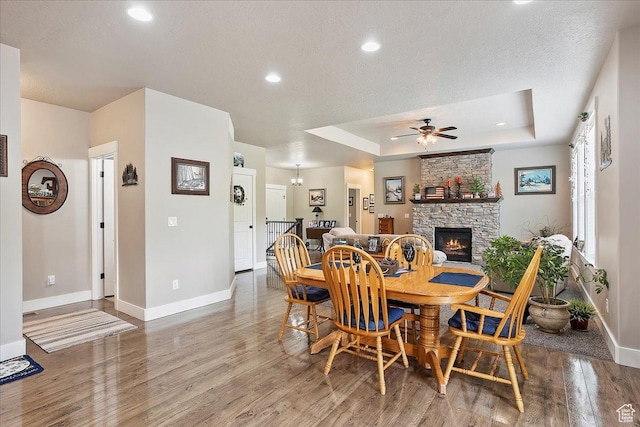4548 N Sheep Creek Dr, Eden, UT 84310 - dining room featuring baseboards, wood finished floors, a fireplace, a ceiling fan, and a tray ceiling