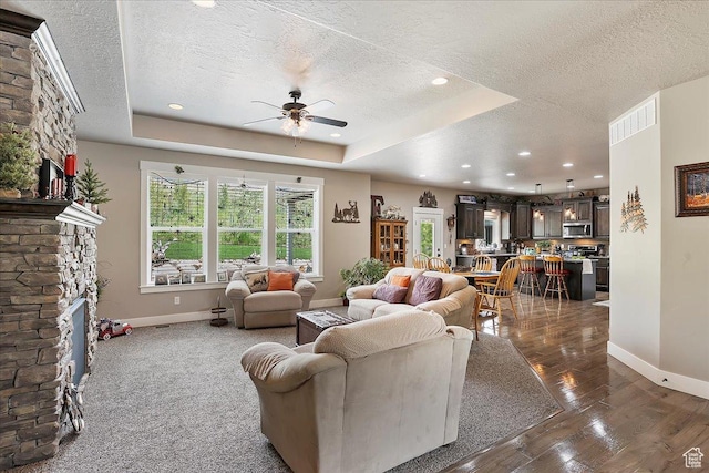 4548 N Sheep Creek Dr, Eden, UT 84310 - living room featuring a textured ceiling, baseboards, a ceiling fan, a stone fireplace, and dark wood-style floors