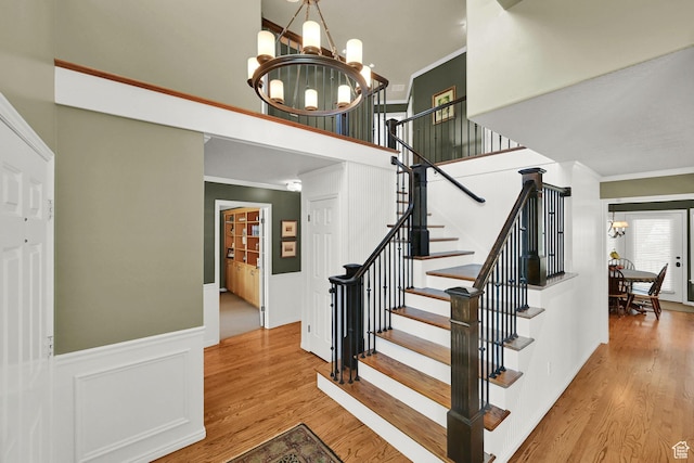 6782 S Courtland Ave, Cottonwood Heights, UT 84121 - stairway featuring a chandelier, crown molding, wood finished floors, a wainscoted wall, and a towering ceiling