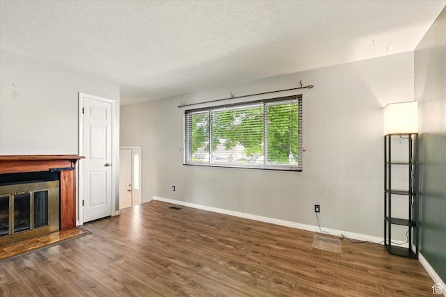 425 E 1200 N, Logan, UT 84341 - unfurnished living room featuring a glass covered fireplace, baseboards, wood finished floors, and a textured ceiling