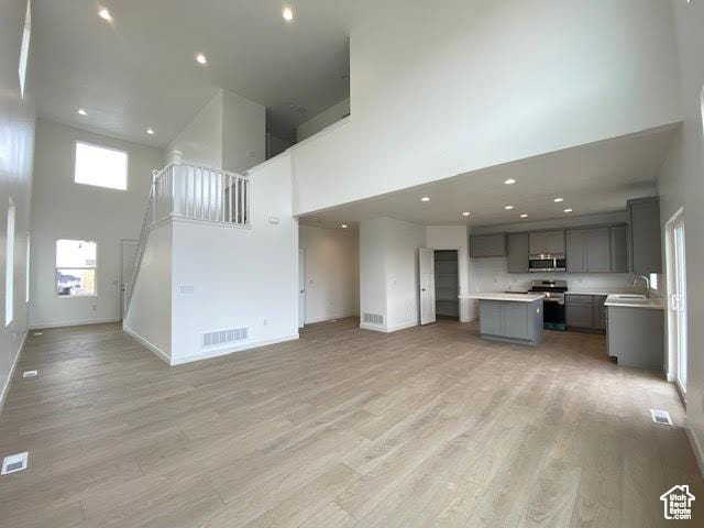 436 W Sapphire Dr Unit 7013, Tooele, UT 84074 - unfurnished living room with a high ceiling, baseboards, light wood-style floors, a sink, and recessed lighting