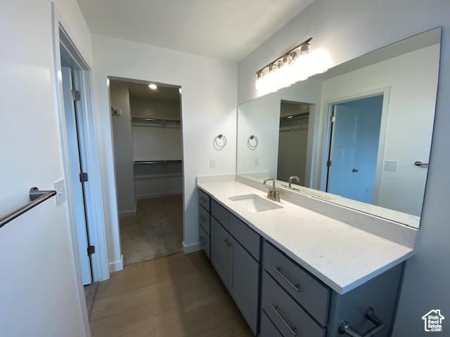 436 W Sapphire Dr Unit 7013, Tooele, UT 84074 - bathroom featuring vanity, a spacious closet, wood finished floors, and baseboards
