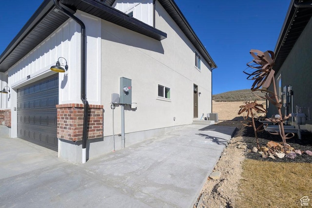 7936 N Bristlecone Rd, Eagle Mountain, UT 84005 - view of side of home with board and batten siding, a garage, brick siding, and driveway