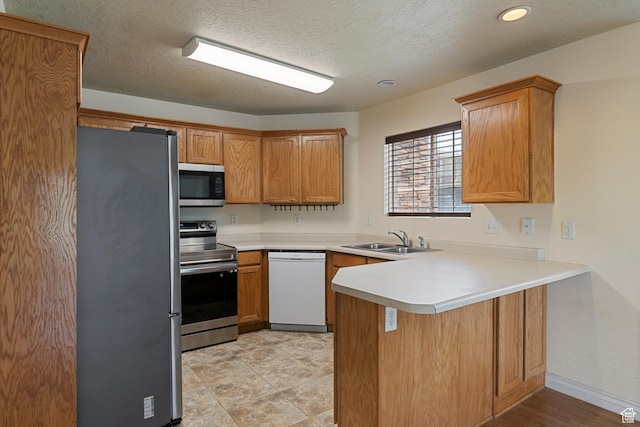 191 E Spencer Peak Way Unit I2, Draper, UT 84020 - kitchen with appliances with stainless steel finishes, a sink, a peninsula, light countertops, and a textured ceiling