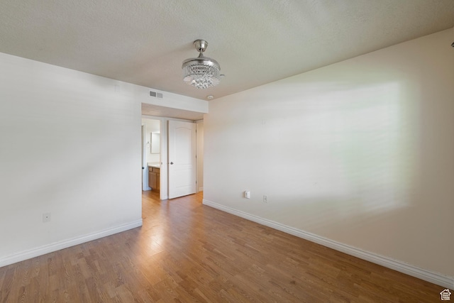 191 E Spencer Peak Way Unit I2, Draper, UT 84020 - empty room featuring baseboards, light wood-type flooring, a chandelier, and a textured ceiling