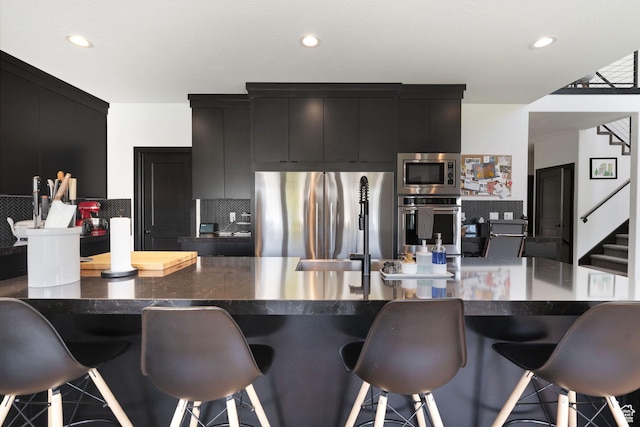 189 N 20 W, Vineyard, UT 84059 - kitchen featuring stainless steel appliances, dark cabinets, a breakfast bar area, backsplash, and recessed lighting