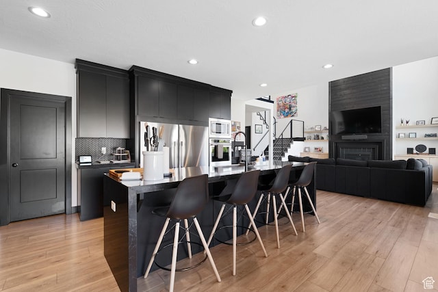 189 N 20 W, Vineyard, UT 84059 - kitchen featuring appliances with stainless steel finishes, dark cabinetry, a kitchen bar, a kitchen island with sink, and dark countertops