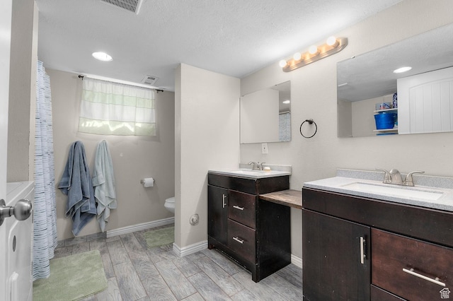 165 N 800 E, American Fork, UT 84003 - bathroom with two vanities, wood tiled floors, toilet, baseboards, and a textured ceiling