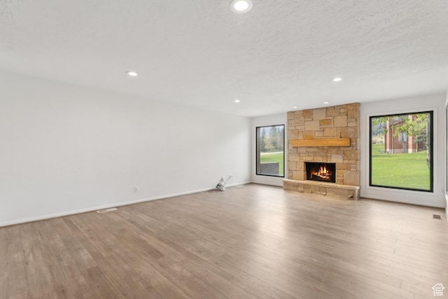 1679 Village Round Dr, Park City, UT 84098 - unfurnished living room with healthy amount of natural light, a stone fireplace, recessed lighting, wood finished floors, and baseboards