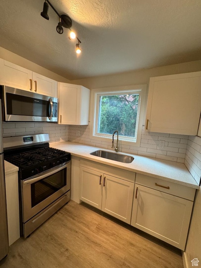 376 E Broadway, Salt Lake City, UT 84111 - kitchen with stainless steel appliances, a sink, a textured ceiling, light wood-style floors, and light countertops