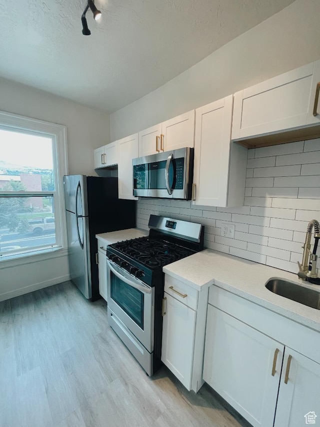 376 E Broadway, Salt Lake City, UT 84111 - kitchen featuring appliances with stainless steel finishes, a sink, light countertops, white cabinetry, and a textured ceiling