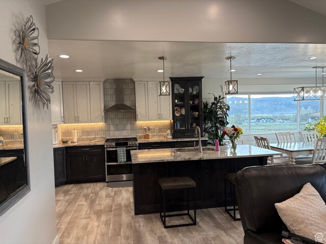 765 E Union St, Manti, UT 84642 - kitchen with range with two ovens, a sink, wall chimney range hood, a breakfast bar area, and light stone countertops