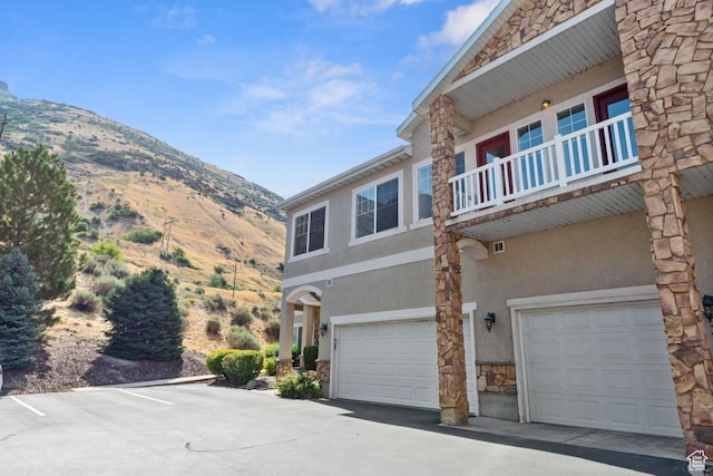 1183 S Canyon Meadow Dr Unit 2, Provo, UT 84606 - view of side of home featuring stone siding, a mountain view, stucco siding, a garage, and a balcony