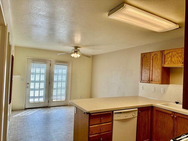 1612 S Talon Dr, Logan, UT 84321 - kitchen featuring dishwasher, a peninsula, light countertops, brown cabinetry, and a ceiling fan