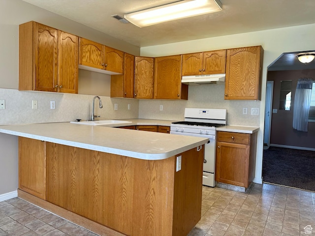 1612 S Talon Dr, Logan, UT 84321 - kitchen featuring white gas range, under cabinet range hood, a sink, a peninsula, and light countertops