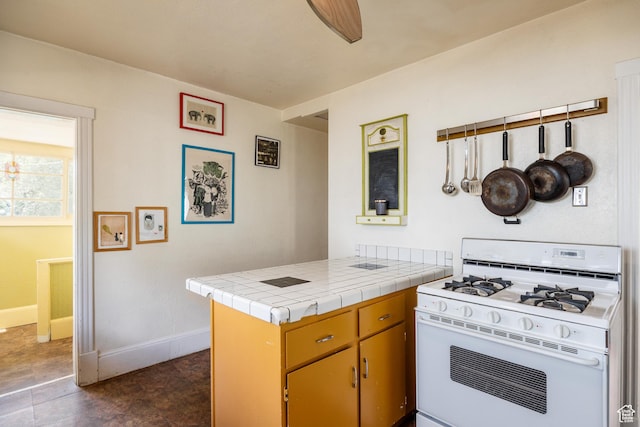 1190 E Sherman Ave S, Salt Lake City, UT 84105 - kitchen featuring white gas range, a peninsula, baseboards, and tile counters