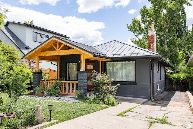 1190 E Sherman Ave S, Salt Lake City, UT 84105 - view of front of house with a standing seam roof, covered porch, a chimney, brick siding, and metal roof