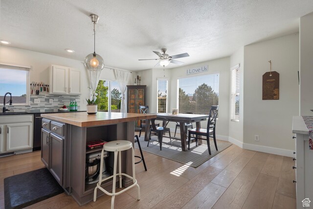 4952 W Buffalo Ct S, Riverton, UT 84096 - kitchen with a sink, a breakfast bar area, light wood-type flooring, backsplash, and ceiling fan