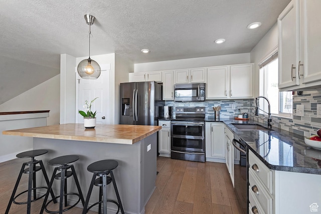 4952 W Buffalo Ct S, Riverton, UT 84096 - kitchen with stainless steel appliances, butcher block counters, a breakfast bar, white cabinetry, and recessed lighting