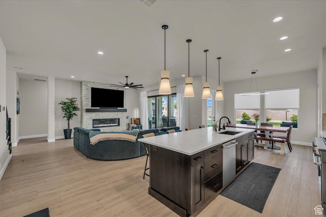 2725 E Ashwood Ln, St George, UT 84790 - kitchen with stainless steel dishwasher, a ceiling fan, light countertops, a stone fireplace, and dark brown cabinetry