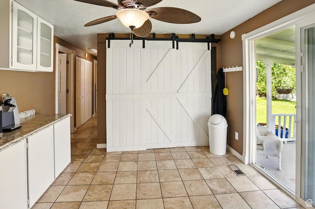2226 W 1000 N, Tremonton, UT 84337 - interior space featuring ceiling fan, a barn door, light tile patterned floors, and baseboards