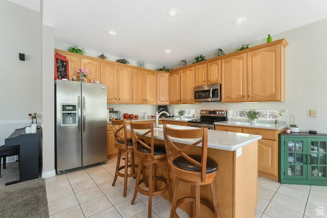 1169 W Bateman Dr, West Jordan, UT 84084 - kitchen with appliances with stainless steel finishes, light tile patterned floors, light countertops, a kitchen island with sink, and recessed lighting