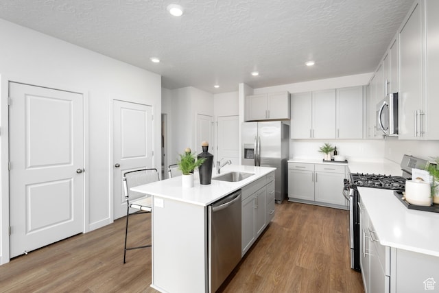 2476 N Wildwood Ln E Unit 249, Heber City, UT 84032 - kitchen with appliances with stainless steel finishes, a kitchen breakfast bar, wood finished floors, a textured ceiling, and a center island with sink