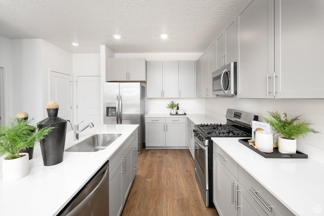 2476 N Wildwood Ln E Unit 249, Heber City, UT 84032 - kitchen with appliances with stainless steel finishes, a sink, a textured ceiling, dark wood-type flooring, and light countertops