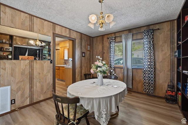 12525 S 1300 E, Draper, UT 84020 - dining room with a chandelier, light wood-style flooring, wooden walls, a textured ceiling, and ornamental molding