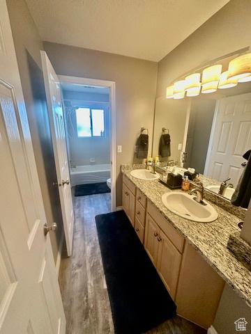 341 E Wilford Ave, Murray, UT 84107 - bathroom with double vanity, toilet, wood finished floors, and shower / bath combination
