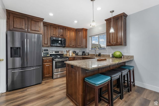 1107 N Independence Ave W, Provo, UT 84604 - kitchen with stainless steel appliances, a peninsula, light stone counters, wood finished floors, and a breakfast bar area