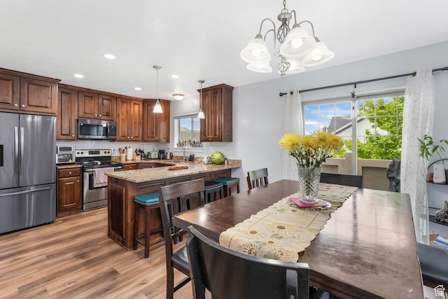 1107 N Independence Ave W, Provo, UT 84604 - kitchen featuring stainless steel appliances, a peninsula, a chandelier, light wood finished floors, and healthy amount of natural light